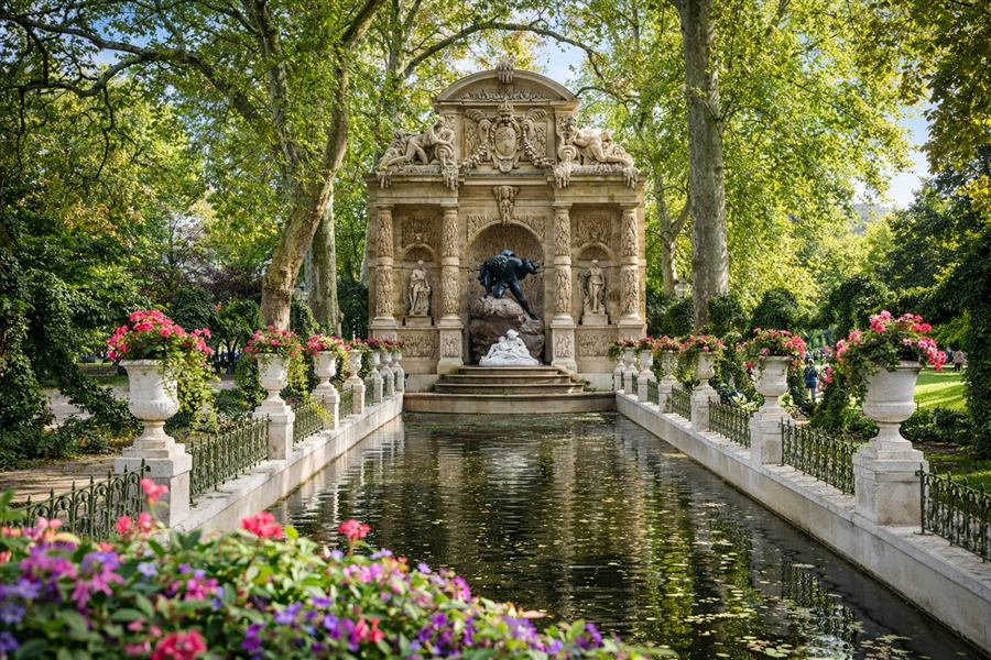 The Medici Fountain in the Luxembourg Gardens surrounded by flowers.